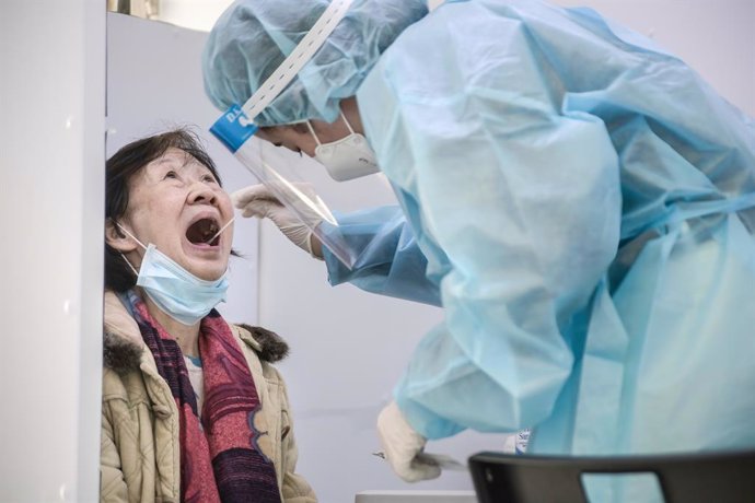 Archivo - 23 January 2021, China, Hong Kong: A health worker wearing a protective suit takes a swab sample from a woman in a test truck during lockdown imposed by the government to curb the spread of the pandemic. Photo: Ivan Abreu/SOPA Images via ZUMA 