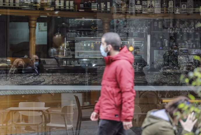 Un hombre camina frente a un bar el primer día de la apertura de la hostelería en Valencia