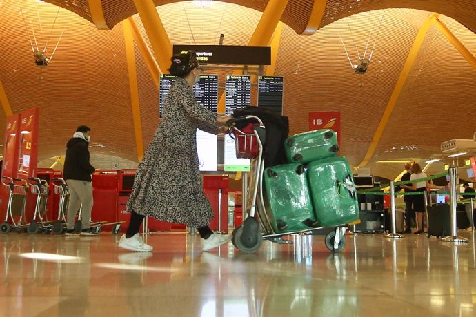 Una mujer camina con varias maletas en un carro en la terminal T4 del Aeropuerto Adolfo Suárez Madrid-Barajas, en Madrid (España), a 15 de marzo de 2021. El Gobierno ha prorrogado hasta el próximo 30 de marzo la limitación de los vuelos directos y buque