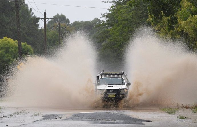 20 March 2021, Australia, Sydney: A car drives through a closed road at Yarramundi Lane. After days of heavy rain showers, the Bureau of Meteorology issued a severe weather warning for people in the state of New South Wales and warned of potentially lif
