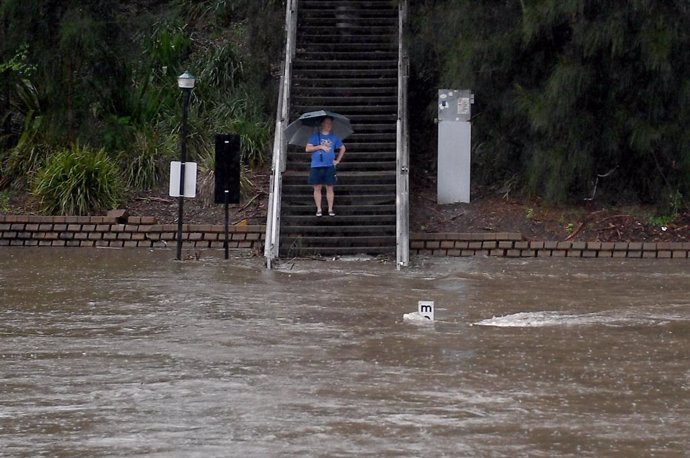 20 March 2021, Australia, Sydney: A man watches the Parramatta river breaking its banks at the Charles St weir and ferry wharf, due to heavy rains. The Bureau of Meteorology issued a severe weather warning for people in the state of New South Wales and 