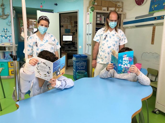 Docentes en el hospital junto a dos pacientes leyendo Ona la Tiburona y el comic de Medusas