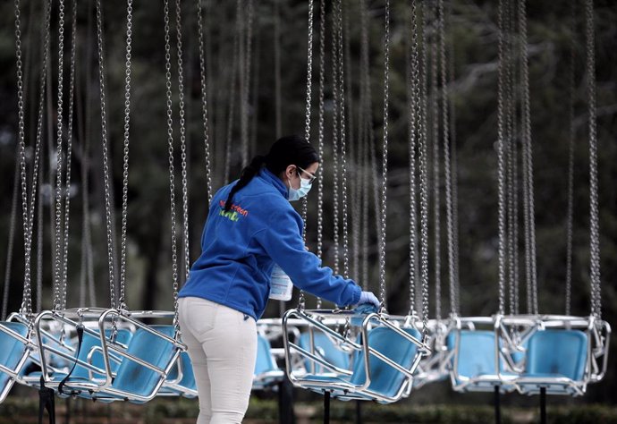 Una operaria de la limpieza desinfecta `las sillas voladoras del Parque de Atracciones durante el Día del Padre, en Madrid (España), a 19 de marzo de 2021. El Parque de Atracciones reabrió el pasado 6 de marzo con un aforo limitado del 60%, una distancia