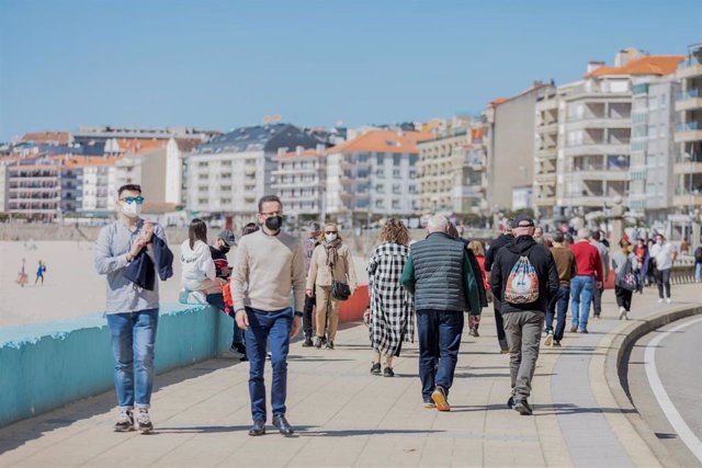 Varias personas pasean por el paseo marítimo de Sanxenxo, Pontevedra, Galicia (España) durante el puente de San José