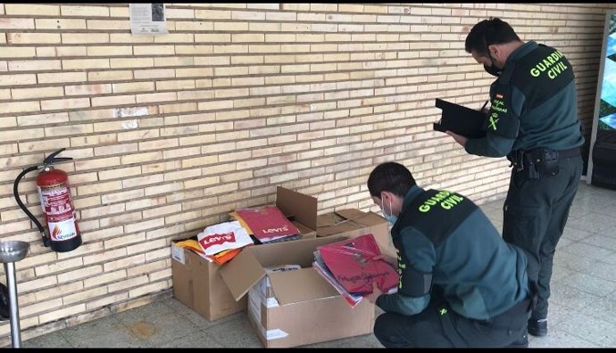 Agentes de la Guardia Civil con las prendas de ropa de marcas falsificadas incautadas en un mercadillo