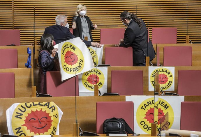 Diputados de Compromís colocan carteles en sus escaños por el cierre de la nuclear de Cofrentes, en un pleno en Les Corts