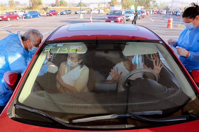 Dos personas reciben la vacuna contra la COVID-19 en su coche, en Tonala, México.