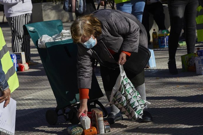 Una mujer recoge los productos de alimentación donados por parte de la Despensa Solidaria de Chamberí durante la concentración y reparto de alimentos a familias vulnerables.