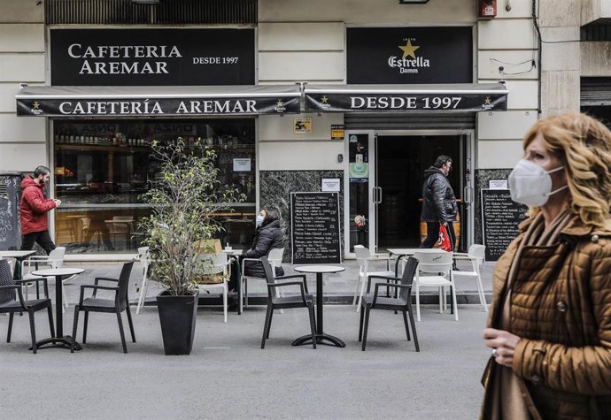 Un mujer camina frente a una terraza el primer día de la apertura de la hostelería en la Comunitat