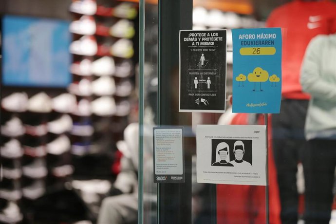 Archivo - Carteles en la entrada a una zapatería en Euskadi