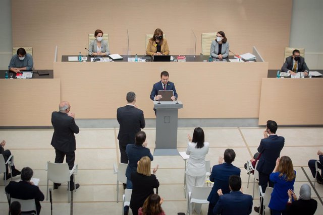 Els diputats d'ERC aplaudeixen drets Pere Aragonès (ERC) després del seu discurs en el debat d'investidura mentre els diputats de Junts estan asseguts al Parlament.
