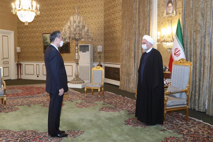 HANDOUT - 26 March 2021, Iran, Tehran: Iranian President Hassan Rouhani (R) receives Chinese Foreign Minister Wang Yi prior to their meeting. Photo: -/Iranian Presidency/dpa - ATTENTION: editorial use only and only if the credit mentioned above is refer