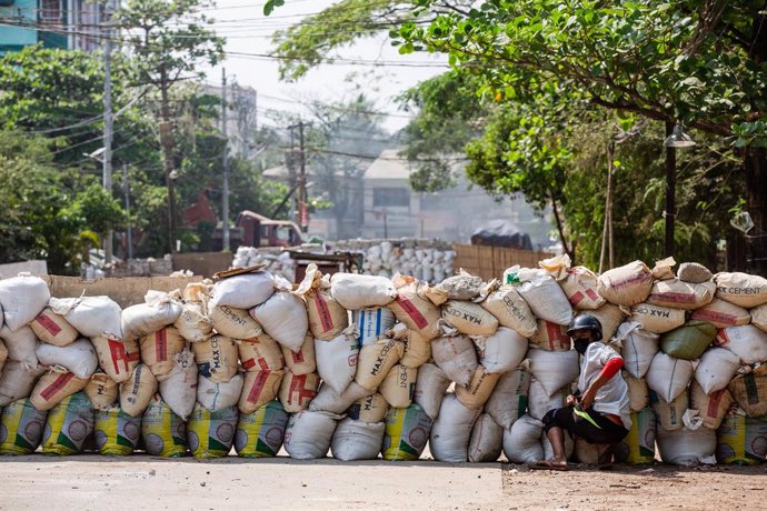 19 March 2021, Myanmar, Yangon: A protester takes cover behind a makeshift barricade during a protest against the military coup and the detention of civilian leaders. Photo: Aung Kyaw Htet/SOPA Images via ZUMA Wire/dpa