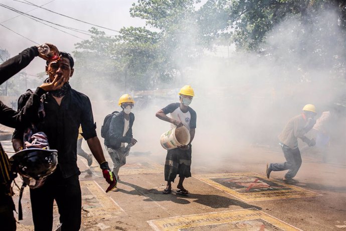 19 March 2021, Myanmar, Yangon: Demonstrators run amid tear gas during clashes at a protest against the military coup and the detention of civilian leaders. Photo: Aung Kyaw Htet/SOPA Images via ZUMA Wire/dpa