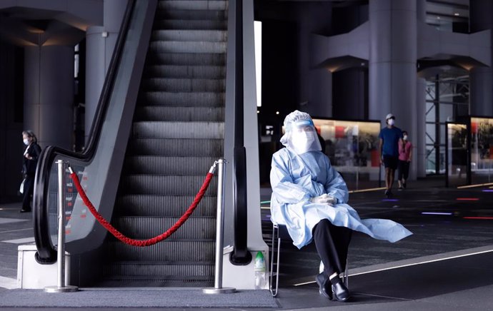 17 March 2021, China, Hong Kong: A medical worker wearing a personal protective equipment suit (PPE) sits next to an escalator at HSBC headquarters in Hong Kong. HSBC Holdings Plc's main Hong Kong office have been closed until further notice after multi
