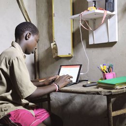 Archivo - Un niño en Senegal carga una tablet con un kit solar fotovoltaico