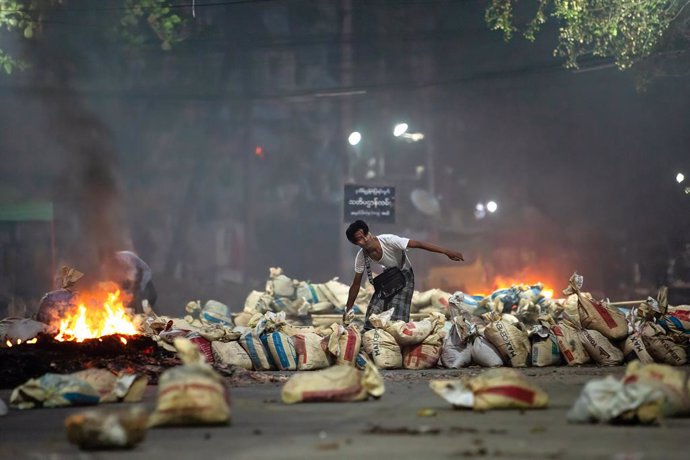 27 March 2021, Myanmar, Yangon: A demonstrator stacks bags on a street as a barricade during a demonstration against the military coup and the detention of civilian leaders. Photo: Theint Mon Soe/SOPA Images via ZUMA Wire/dpa