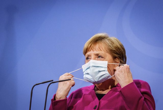 25 March 2021, Berlin: German Chancellor Angela Merkel takes off her face mask before a press statement following the online summit meeting of EU heads of state and government. Photo: Michael Kappeler/dpa-pool/dpa