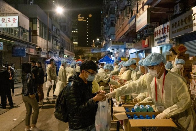 Archivo - 04 February 2021, China, Hong Kong: Health workers wearing personal protective equipment distribute drinks to residents during the mandatory coronavirus testing. Photo: Isaac Wong/SOPA Images via ZUMA Wire/dpa