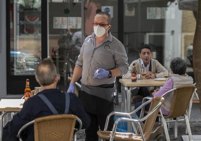 Archivo - Un camarero atiende la terraza de un bar en Sevilla, foto de archivo