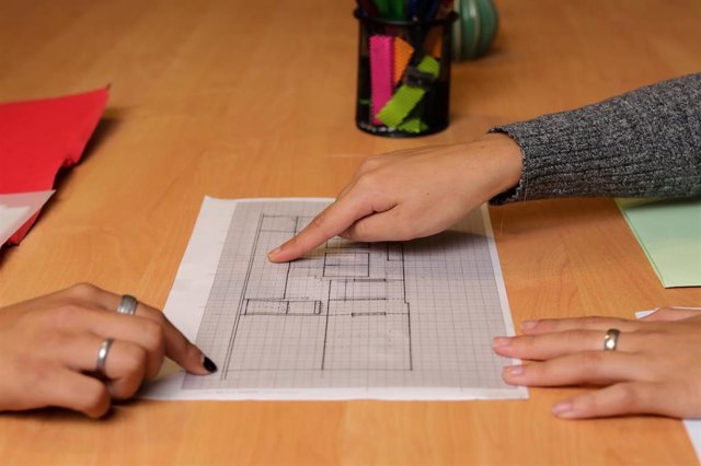 Archivo - Dos chicas señalan sobre el plano de una vivienda.