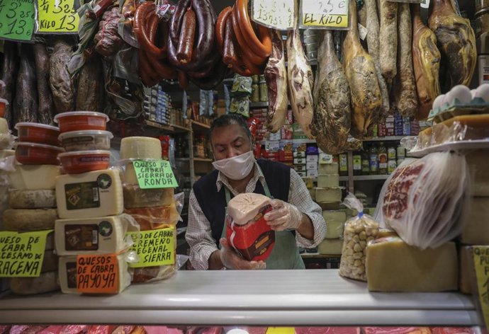 Archivo - Un carnicero trabaja con mascarilla en un mercado.
