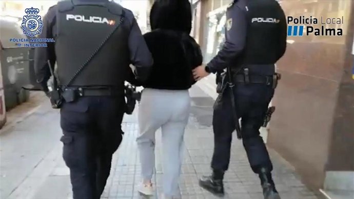 Dos policías escoltan a una persona detenida durante la operación contra un grupo organizado que vendía droga a domicilio en Palma.