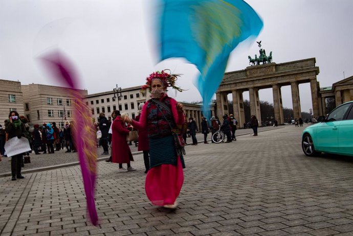 28 February 2021, Berlin: Ademonstrator waves flags as she takes part in the "Multicultural Women's March for Freedom, Tolerance and the Future of Our Children" at Pariser Platz. Photo: Paul Zinken/dpa-Zentralbild/dpa