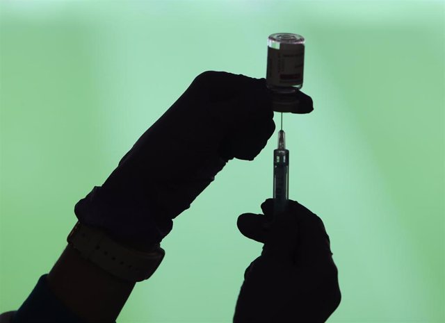Un profesional sanitaria sostiene una jeringuilla y un vial con la vacuna del Covid-19, en un dispositivo instalado en el Estadio Wanda Metropolitano, en Madrid (España), a 30 de marzo de 2021.