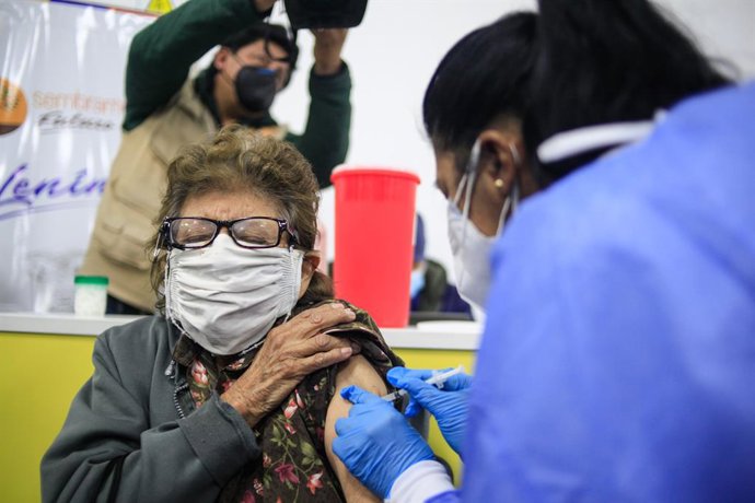 29 March 2021, Ecuador, Quito: An elderly woman receives a dose of the Pfizer-BioNTech coronavirus vaccine in the Quito Bicentennial Convention Center. The vaccination program in Ecuador has begun its first phase, which includes first-line personnel and