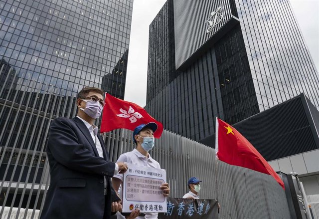 31 March 2021, China, Hong Kong: Pro-Hong Kong Government supporters hold China and Hong Kong flags as they gather outside the Hong Kong government headquarters building to show their support to the government's policy of reforming the electoral system by