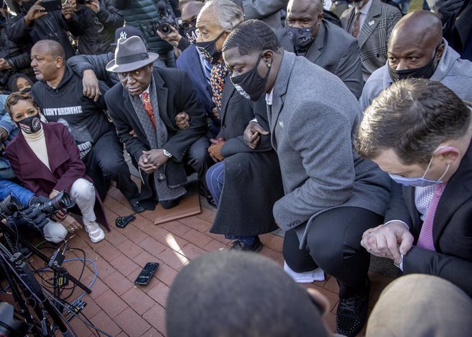 29 March 2021, US, Minneapolis: Floyd family members, civil rights activist and attorney Ben Crump (L) and civil rights activist Al Sharpton kneel for 8 minutes and 46 seconds, outside the Hennepin County Courthouse before the start of the trial of form