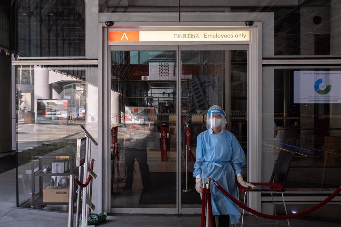 17 March 2021, China, Hong Kong: A medical worker wearing a personal protective equipment suit (PPE) stands at the main entrance of HSBC headquarters in Hong Kong. HSBC Holdings Plc's main Hong Kong office have been closed until further notice after mul
