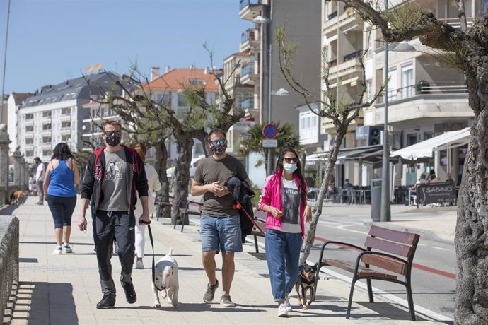 Varias personas pasean por el Paseo Marítimo de Sanxenxo, en Pontevedra, Galicia (España), a 27 de marzo de 2021. El subcomité clínico mantiene el nivel alto de restricciones en el concello de Sanxenxo, lo que conlleva que la hostelería solo puede servi