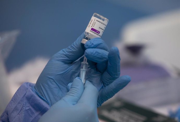 Una profesional sanitaria sostiene una jeringuilla con un vial de la vacuna contra la COVID-19 de AstraZeneca en un dispositivo de vacunación en el pabellón SADUS en Sevilla (Andalucía, España).