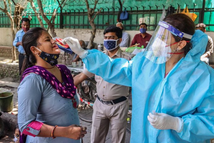 02 April 2021, India, New Delhi: A health worker collects swab sample from a woman for Coronavirus (Covid-19) PCR test at the road side in New Delhi. Photo: Naveen Sharma/SOPA Images via ZUMA Wire/dpa
