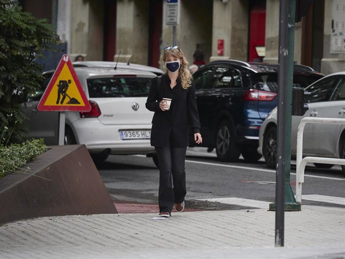 Archivo - Una mujer con mascarilla y un café en la mano en el cuarto día de la Fase 1 en la ciudad de Pamplona