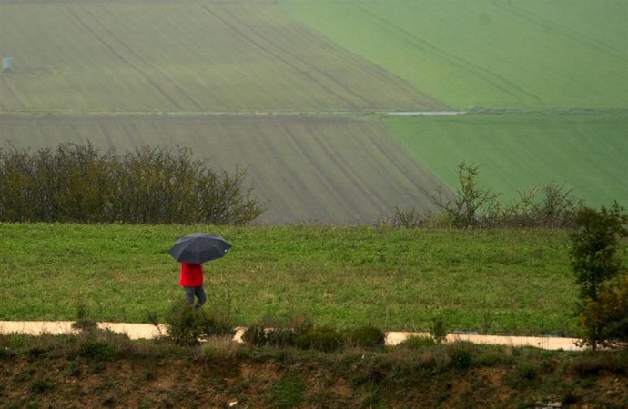 Archivo - Una persona se refugia con un paraguas de la lluvia en Vitoria, País Vasco (España), a 19 de marzo de 2021. 