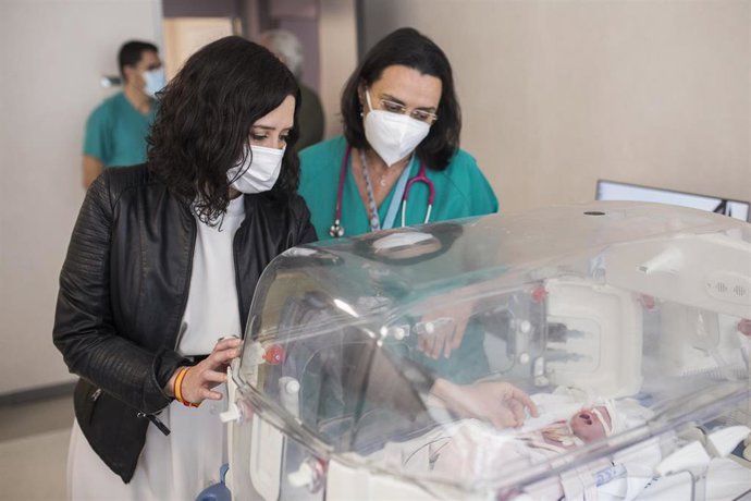 La presidenta de la Comunidad de Madrid, Isabel Díaz Ayuso, observa a un bebé durante su visita al Complejo Hospitalario 12 de Octubre