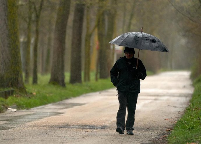 Archivo - Una persona se refugia con un paraguas de la lluvia en Vitoria, País Vasco (España), a 19 de marzo de 2021. Para la jornada de hoy, está activado el aviso amarillo por debajo de los 1.000 metros y habrá precipitaciones débiles moderadas. Las t