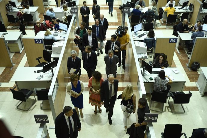 Archivo - La ministra de Hacienda en funciones, María Jesús Montero (con vestido naranja), durante su vista a la delegación especial de la AEAT en Madrid con motivo de la Campaña de Renta 2018.