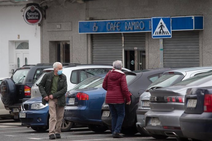 Archivo - Dos personas pasan frente a un bar con las persianas bajadas en una imagen de archivo.