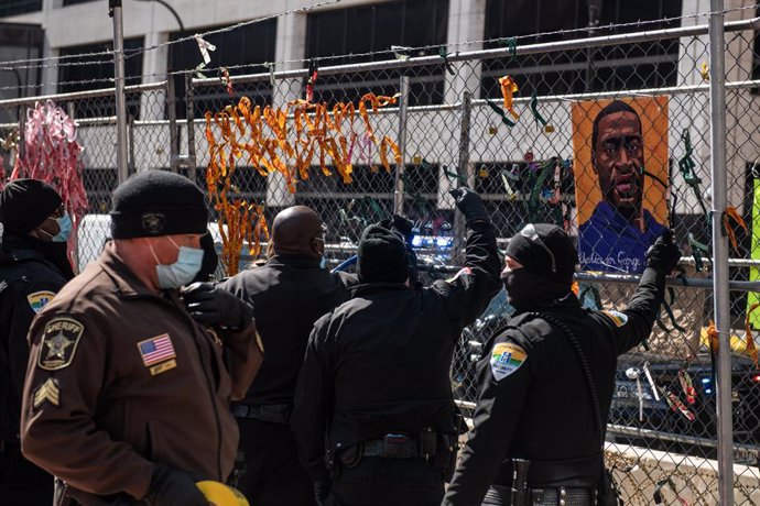 02 April 2021, US, Minneapolis: Police officers remove the photos and locks from the fencing outside the Hennepin County Courthouse, where the trial of a former Minneapolis police officer Derek Chauvin in the death of George Floyd take place. Protestors