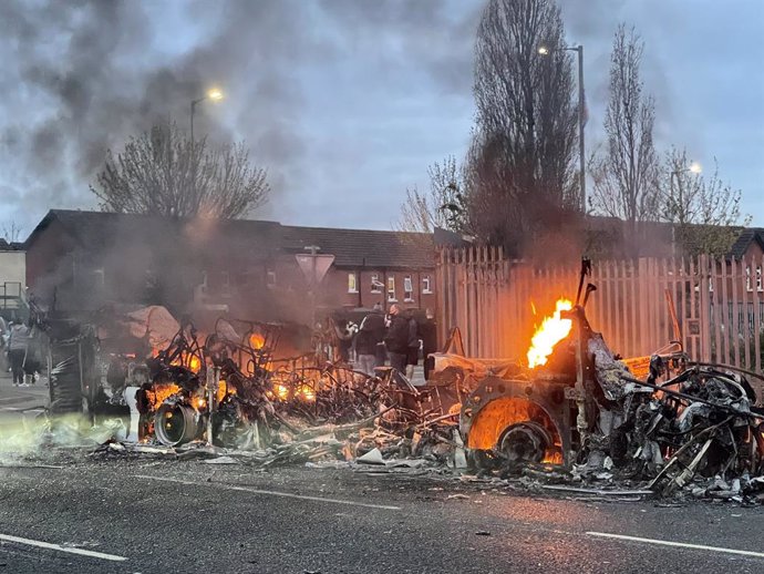 07 April 2021, United Kingdom, Belfast: Wreckage of a Metrobus still on fire during further unrest. Northern Ireland has had several consecutive nights of street violence and disorder in a number of mainly loyalist areas following a controversial decisi