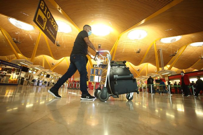 Un hombre camina con varias maletas en un carro en la terminal T4 del Aeropuerto Adolfo Suárez Madrid-Barajas, 