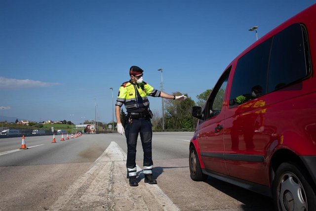 Archivo - Un agente de los Mossos d'Esquadra protegido con una mascarilla en un control en el peaje de La Roca del Vallès pide a un conductor el justificante que le permite su salida, en La Roca del Vallès/Barcelona/Catalunya (España) a 9 de abril de 2020