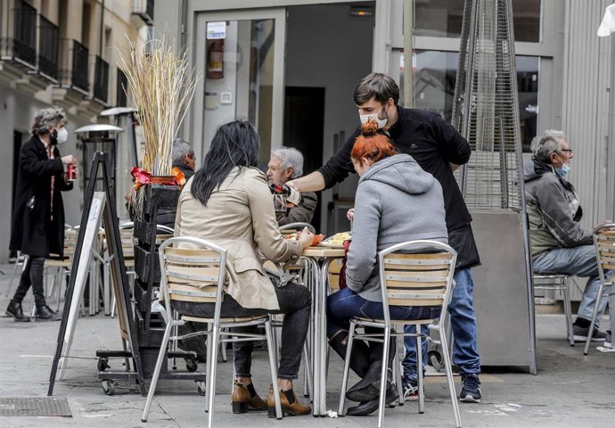 Archivo - Un camarero atiende a dos clientas en una terraza el primer día de la apertura de la hostelería en Valencia