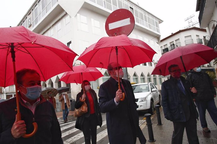 El candidato del PSOE a la Presidencia de la Comunidad de Madrid, Ángel Gabilondo (c), camina con un paraguas durante su visita a varios establecimientos, a 9 de abril de 2021, en Arganda del Rey, Madrid (España). Esta es una de las visitas a municipios