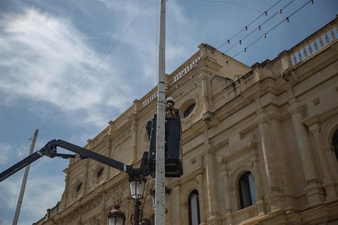 Operario de la empresa instala iluminación especial relacionada con la Feria