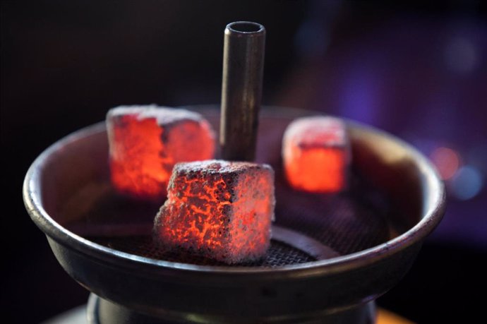 Archivo - 11 February 2019, Hamburg: Glowing coal lies on a metal screen above the tobacco in the head of a water pipe in a shisha bar. The operators of shisha bars in Hamburg are to be obliged by law to protect their guests from carbon monoxide poisoni